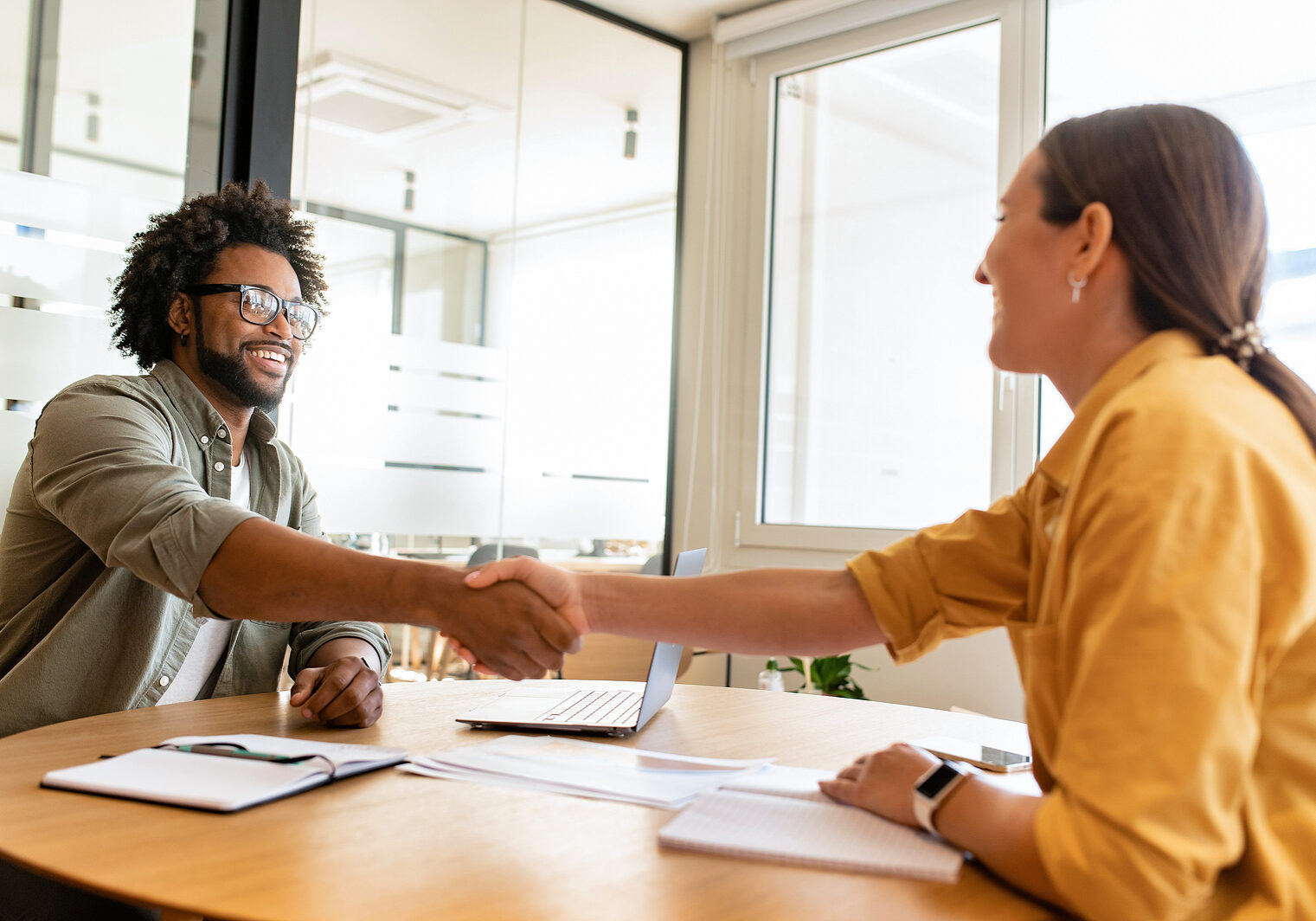 Handsome positive businessman looking at the female colleague, they shaking hands. Collaboration of business partners, workteam, support and agreement concept